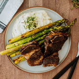 maple bourbon beef short ribs on a plate with mashed potatoes and asparagus 