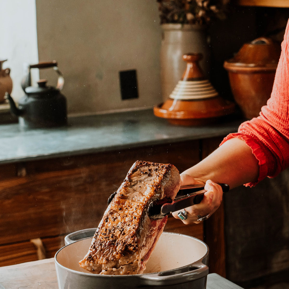 woman searing a beef brisket in a cast iron pot