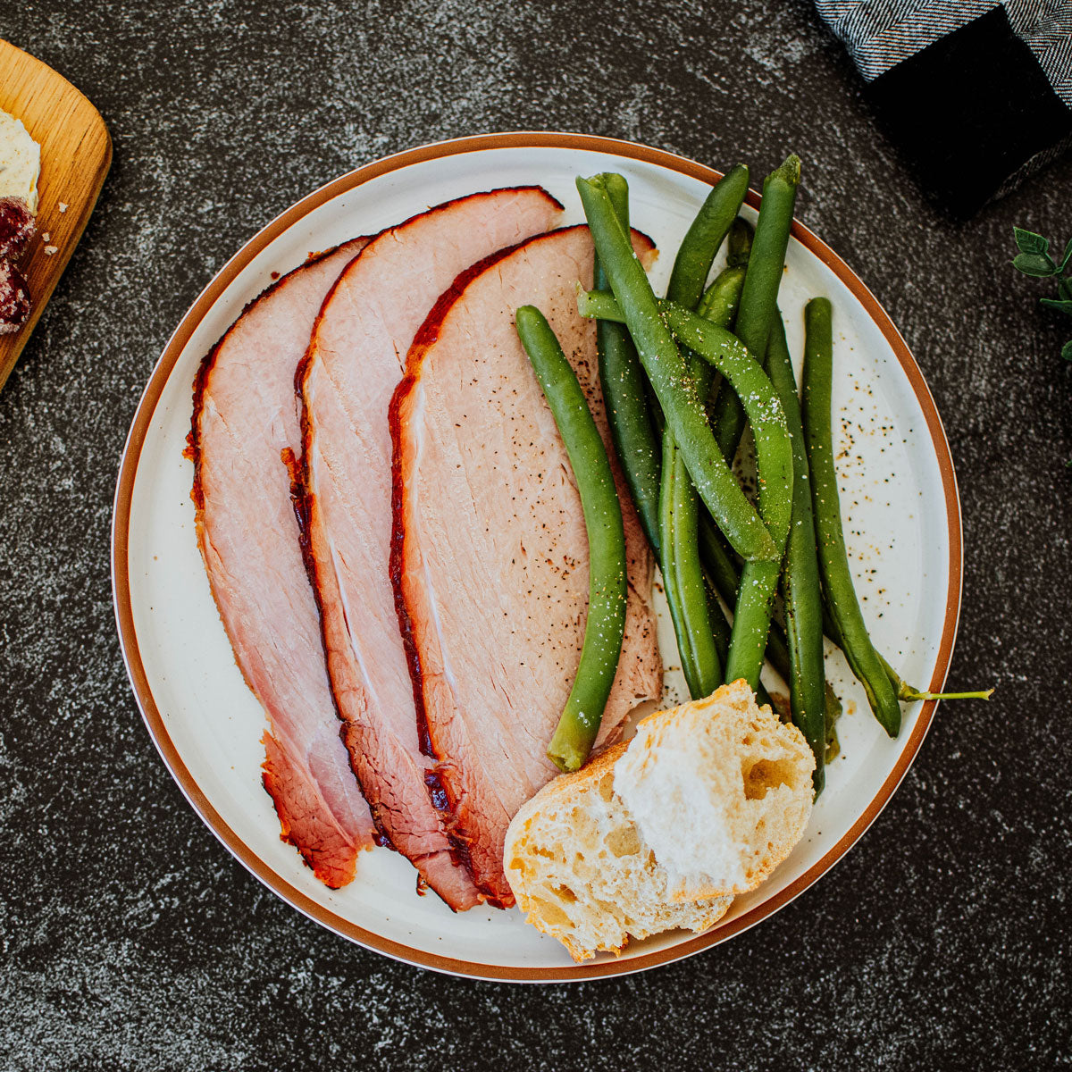 organic  ham on a plate with green beans and bread