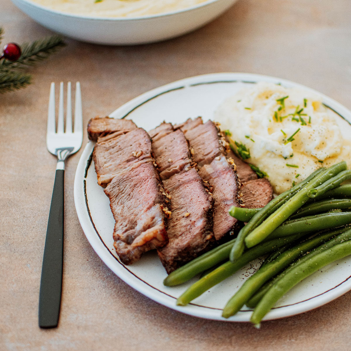 roasted chuck roast sliced on a plate with mashed potatoes and green beans