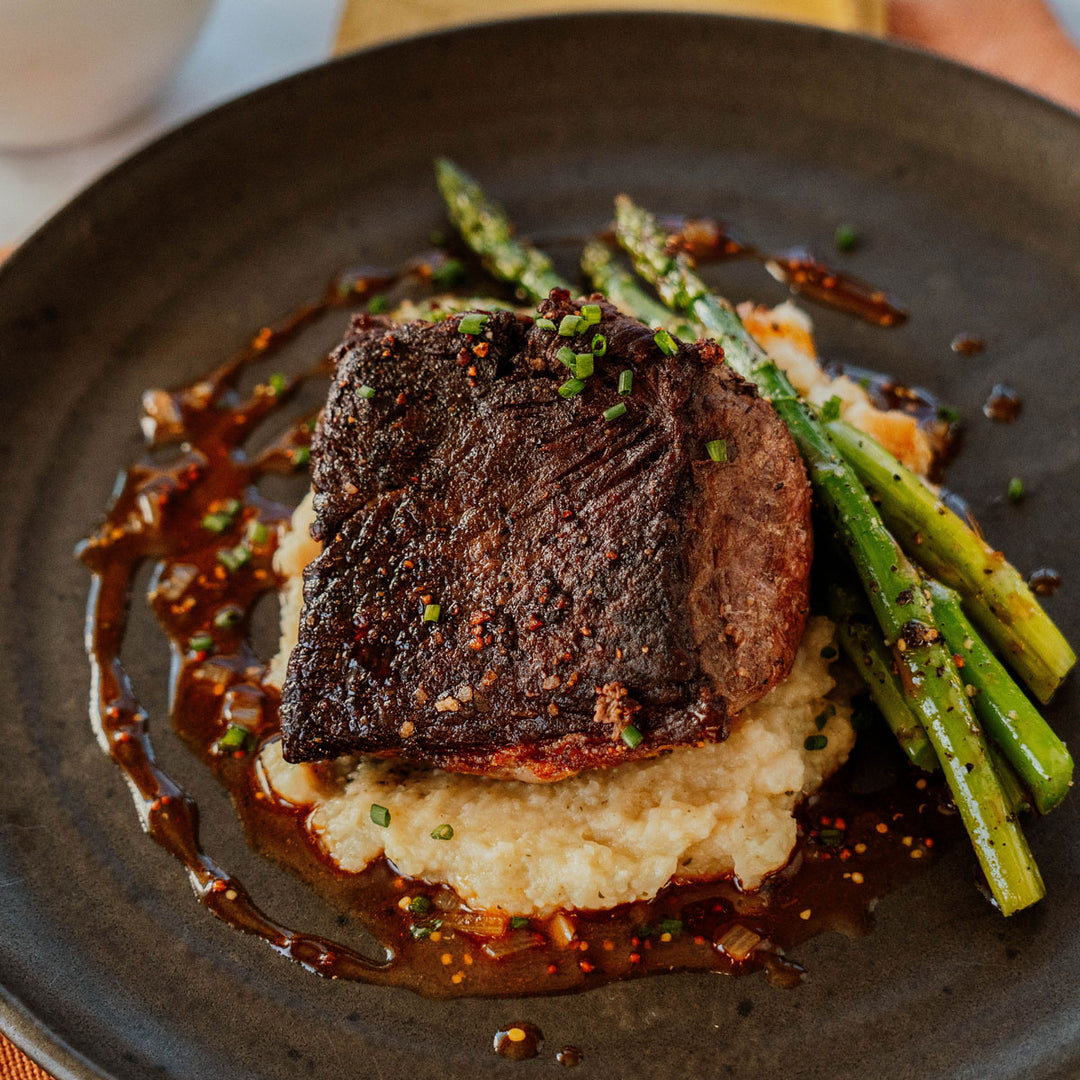 sirlon steak on top of mashed potatoes and apsaragus
